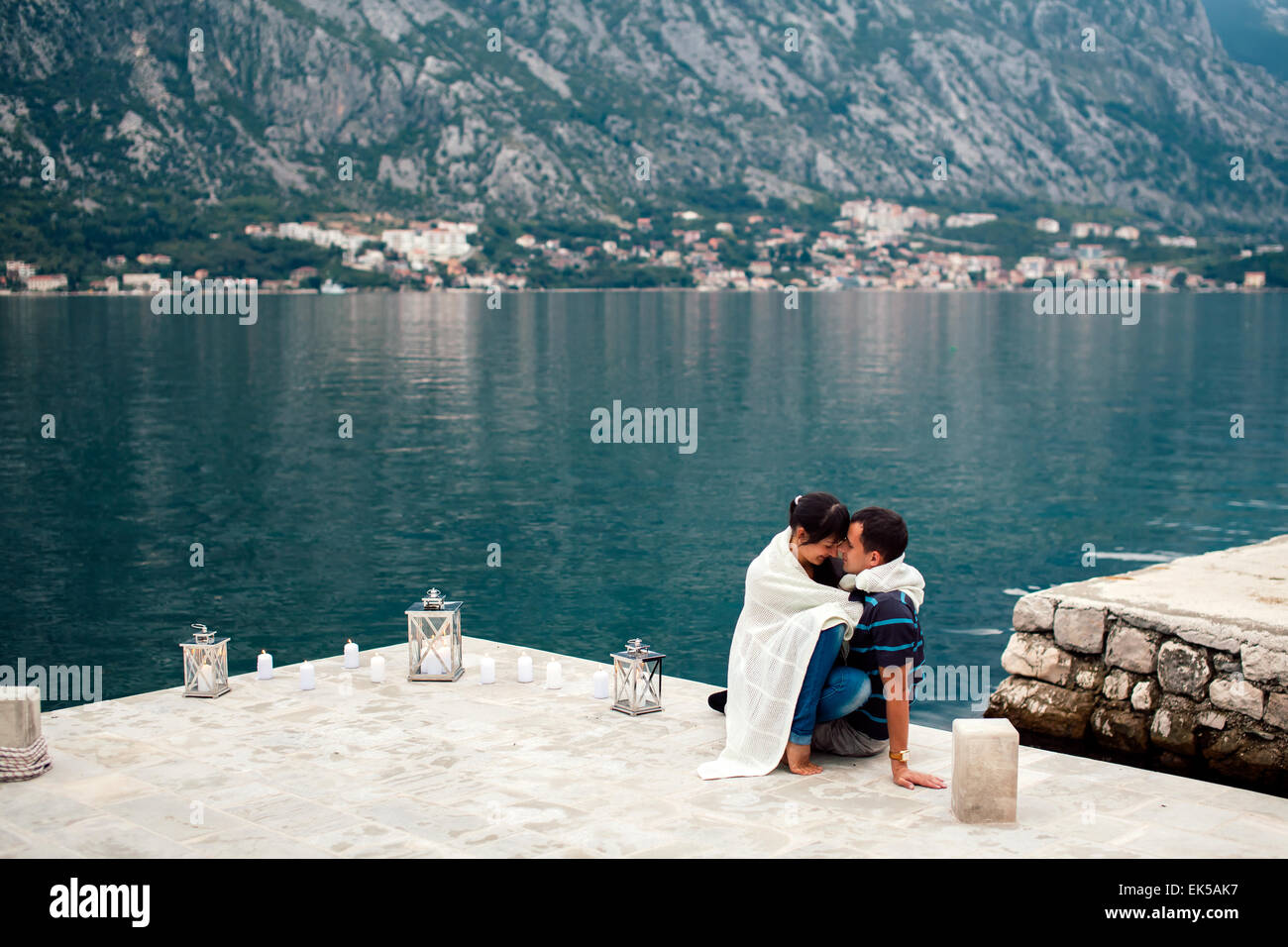 Coppia sulla spiaggia con candkes in un posto romantico con la montagna e la vista sulla baia in Montenegro Foto Stock