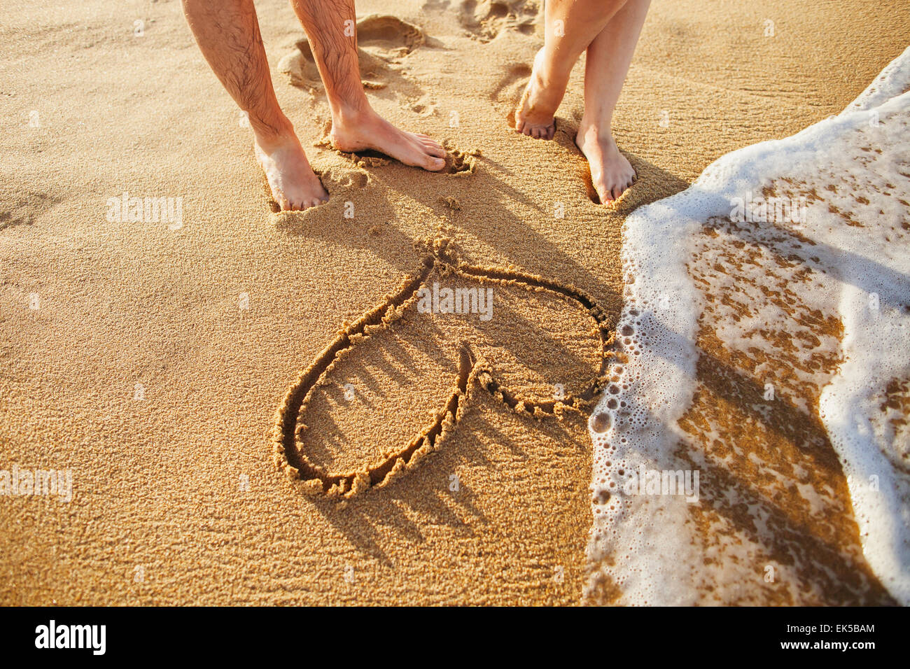 Cuore sulla spiaggia con coppia morchie close up con sea wave Foto Stock