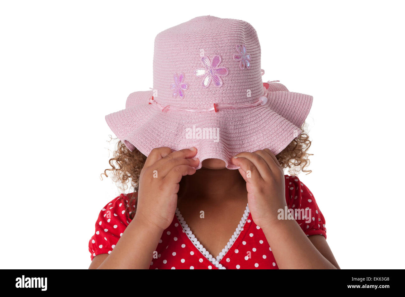 Bambina di cinque anni che si nasconde sotto un cappello rosa su sfondo bianco Foto Stock