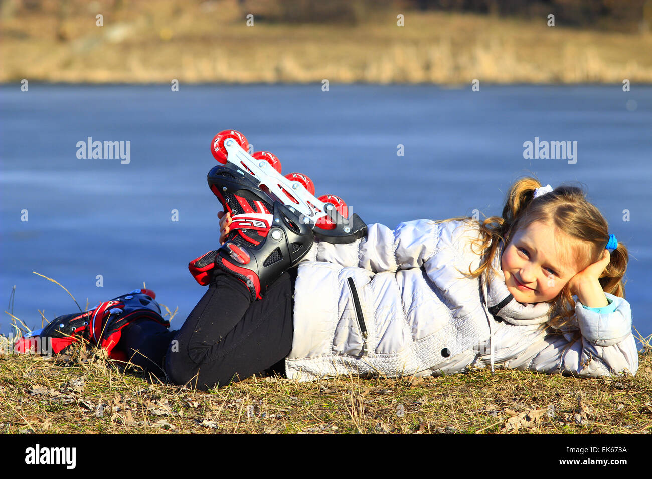 Giovane ragazza in pattini a rotelle giace a terra e sorrisi Foto Stock