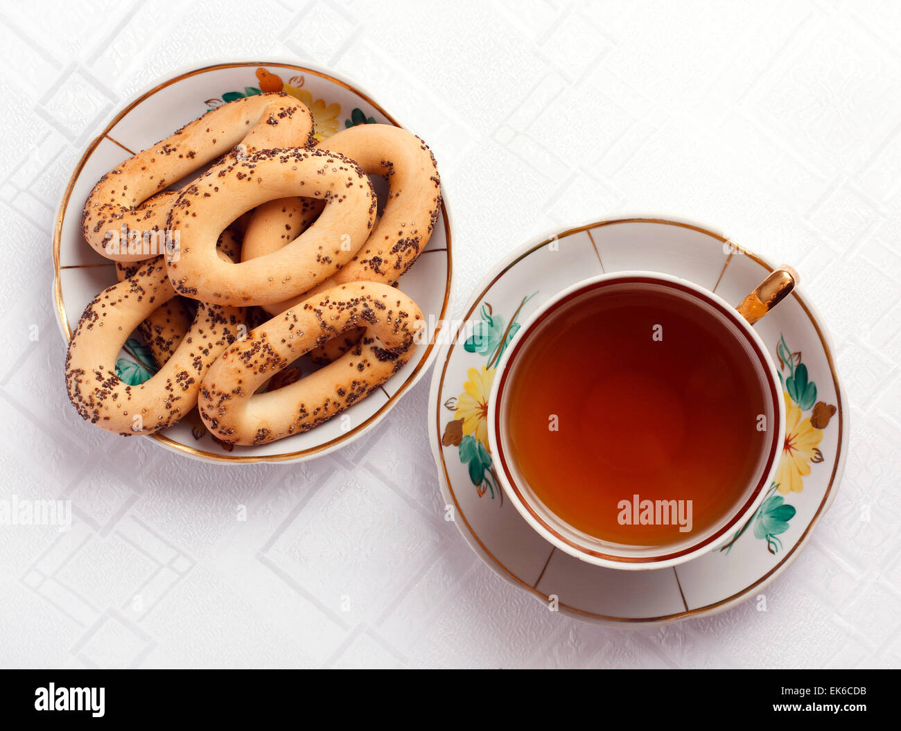 Bagel con semi di papavero e una tazza di tè sulla tovaglia Foto Stock