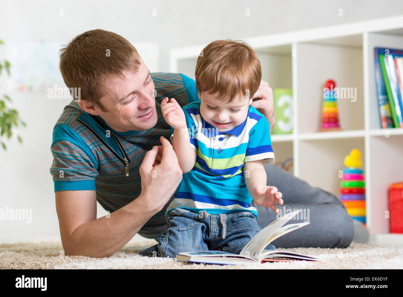 Bambino ragazzo e papà leggere un libro sul pavimento a casa Foto Stock