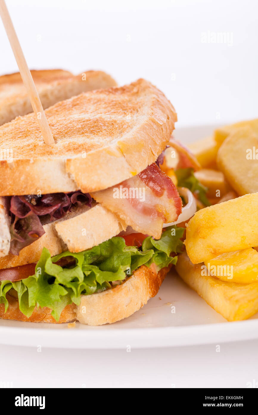Club sandwich a tostare il pane bianco con un ripieno di carne servita con croccante di patate dorate patatine fritte, closeup vista parziale iso Foto Stock