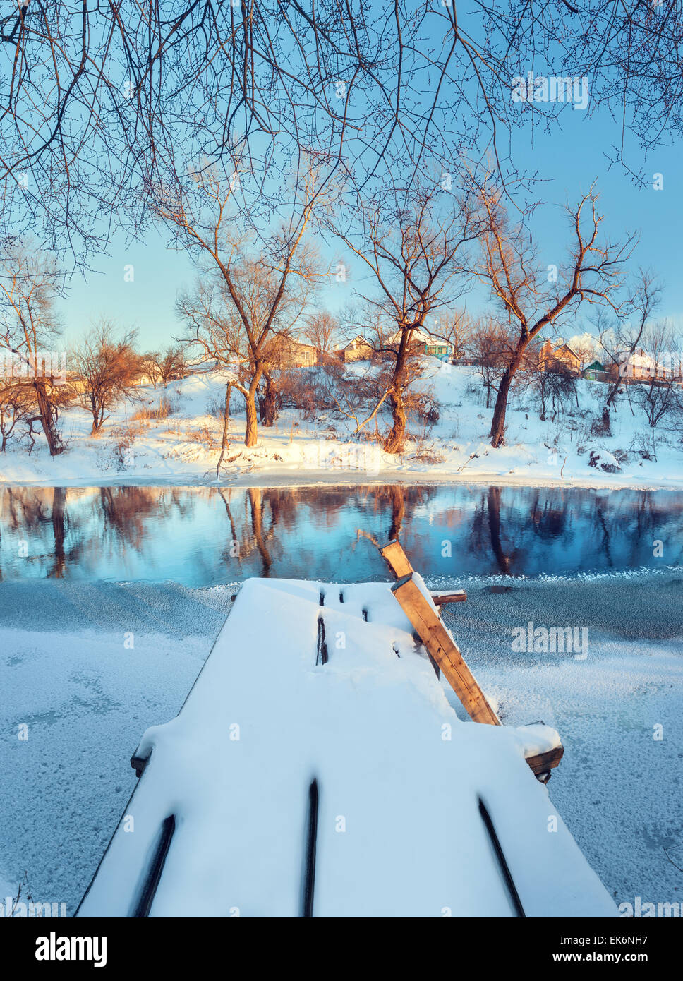 Bel ponte con acqua, neve, cielo blu e rami. Tramonto in inverno presso il fiume Krinka. Foresta in Ucraina Foto Stock