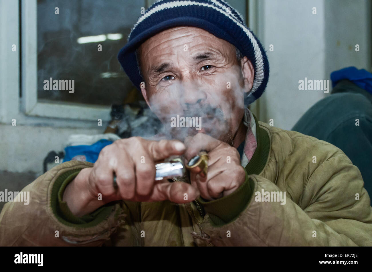 Senzatetto di fumare un tubo mentre in attesa di cibo a Xi'an Soup Kitchen, Cina. Foto Stock