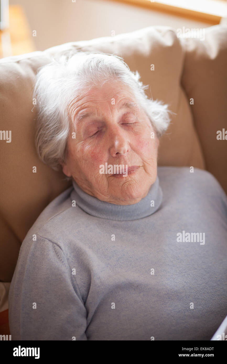 Old Lady addormentato in posizione eretta nella poltrona con sorriso contenti Foto Stock