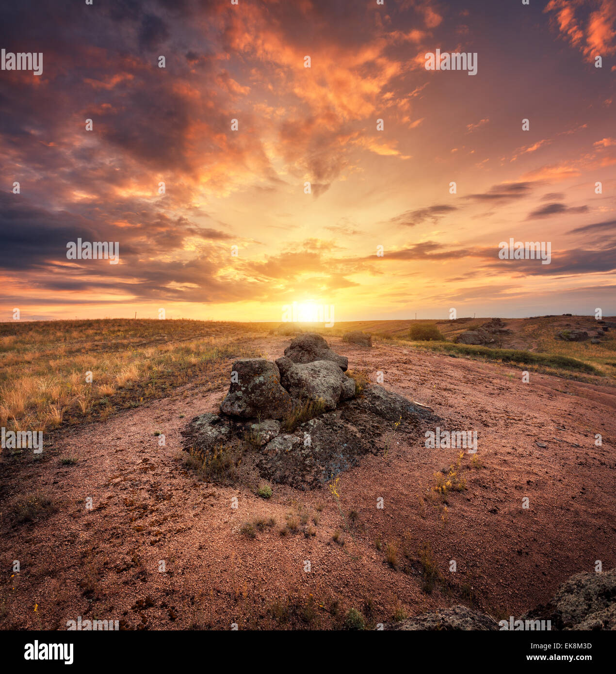 Bella estate tramonto con cielo rosso, arancio nuvole, rocce e erba gialla in Ucraina Foto Stock