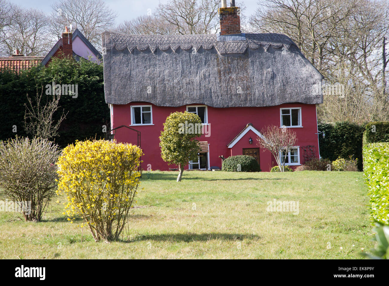 Classico rosso pittoresco paese di paglia cottage in Inghilterra rurale con un prato Foto Stock