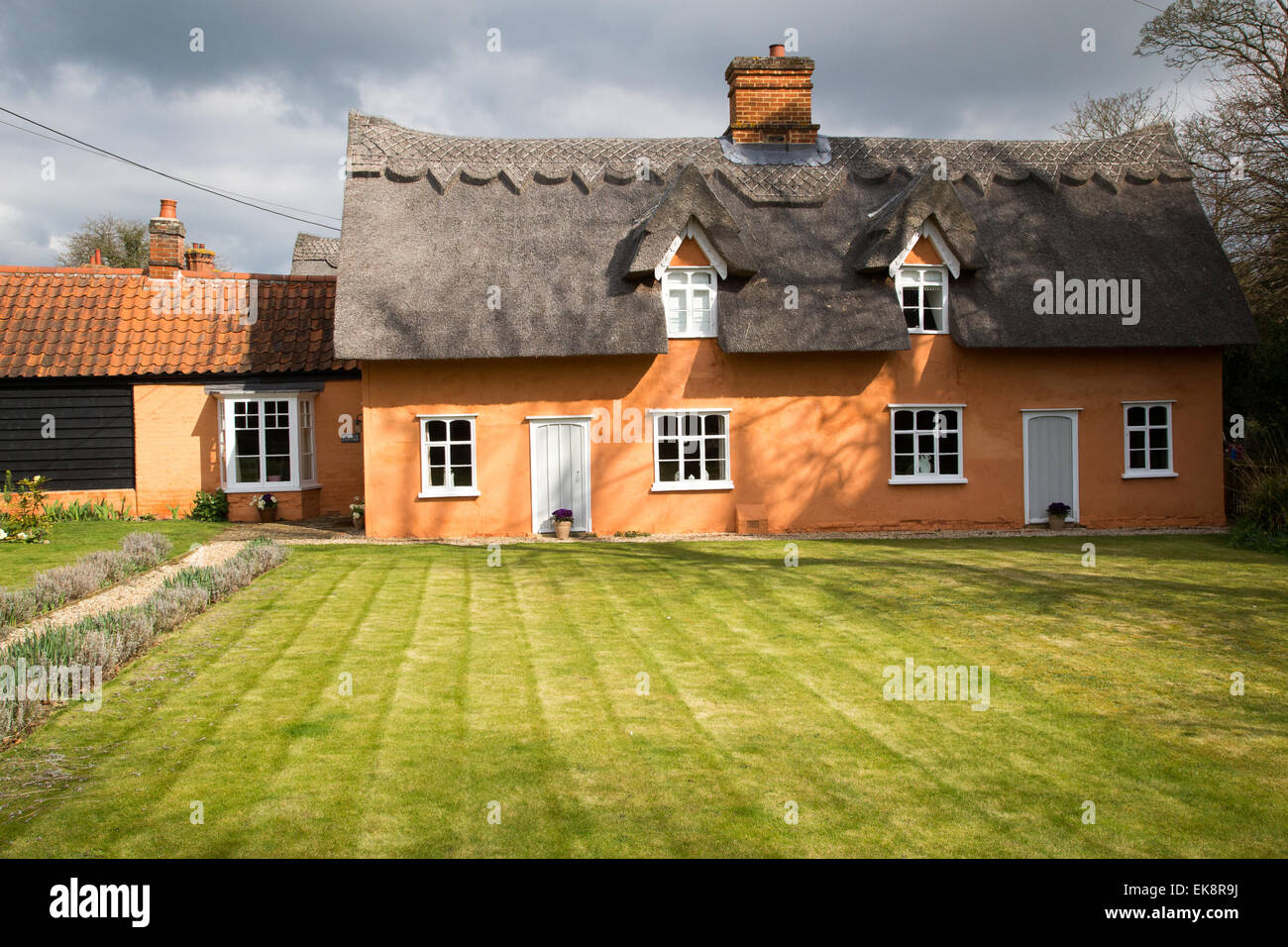 Classic arancio pittoresco paese di paglia cottage in Inghilterra rurale con un prato Foto Stock