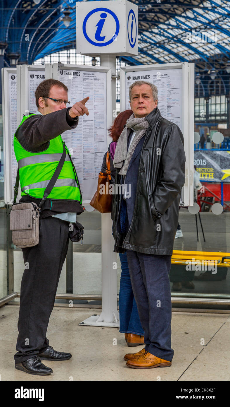 Un'immagine verticale di rete guida il personale del servizio clienti assistenza ai passeggeri con le direzioni ad un terminale occupato Brighton, Sussex England Regno Unito Foto Stock