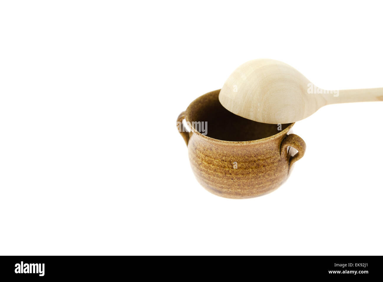 Vaso piccolo con un cucchiaio di legno isolato su bianco Foto Stock