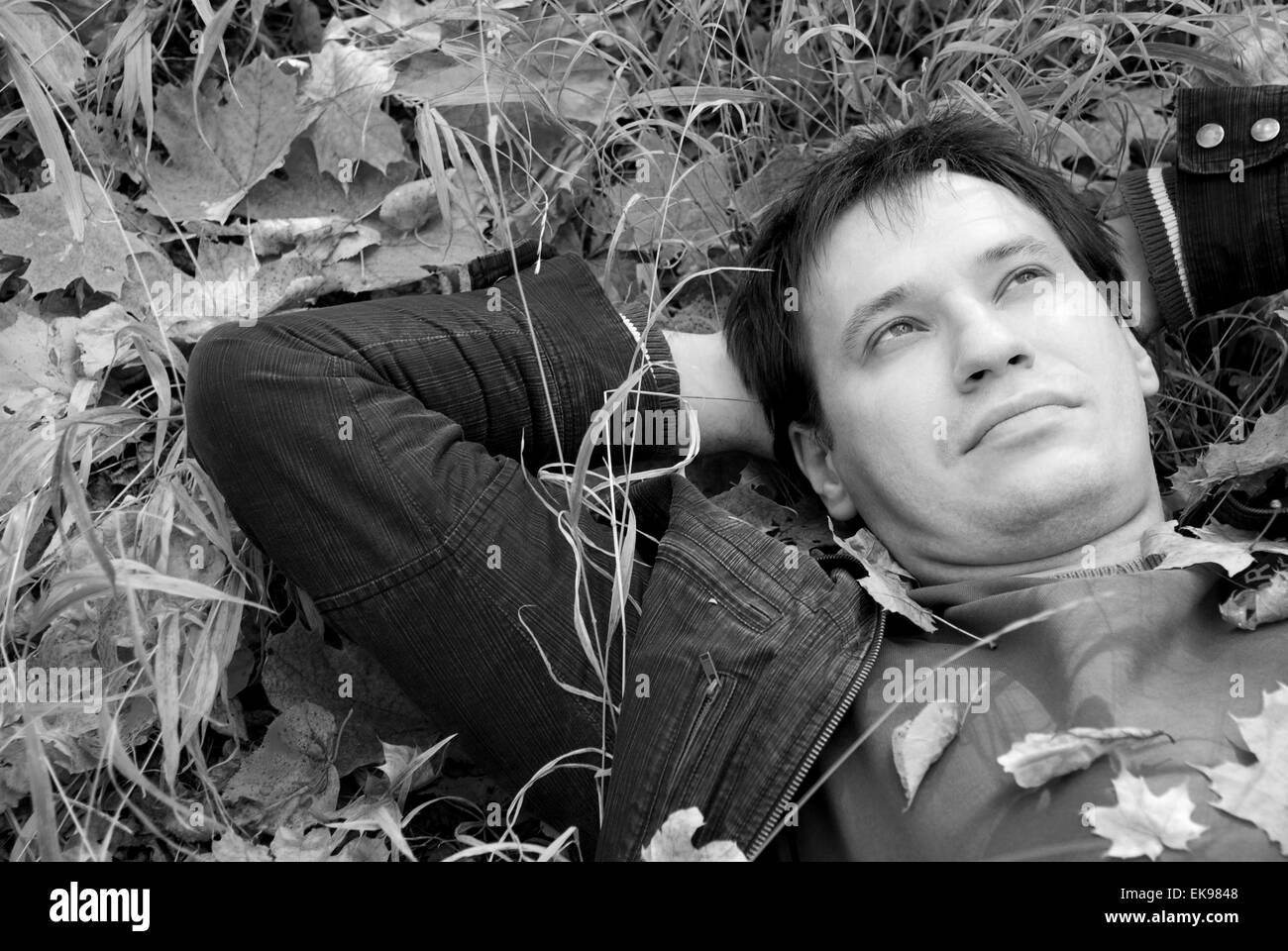 Ritratto di un uomo disteso su foglie di autunno Foto Stock