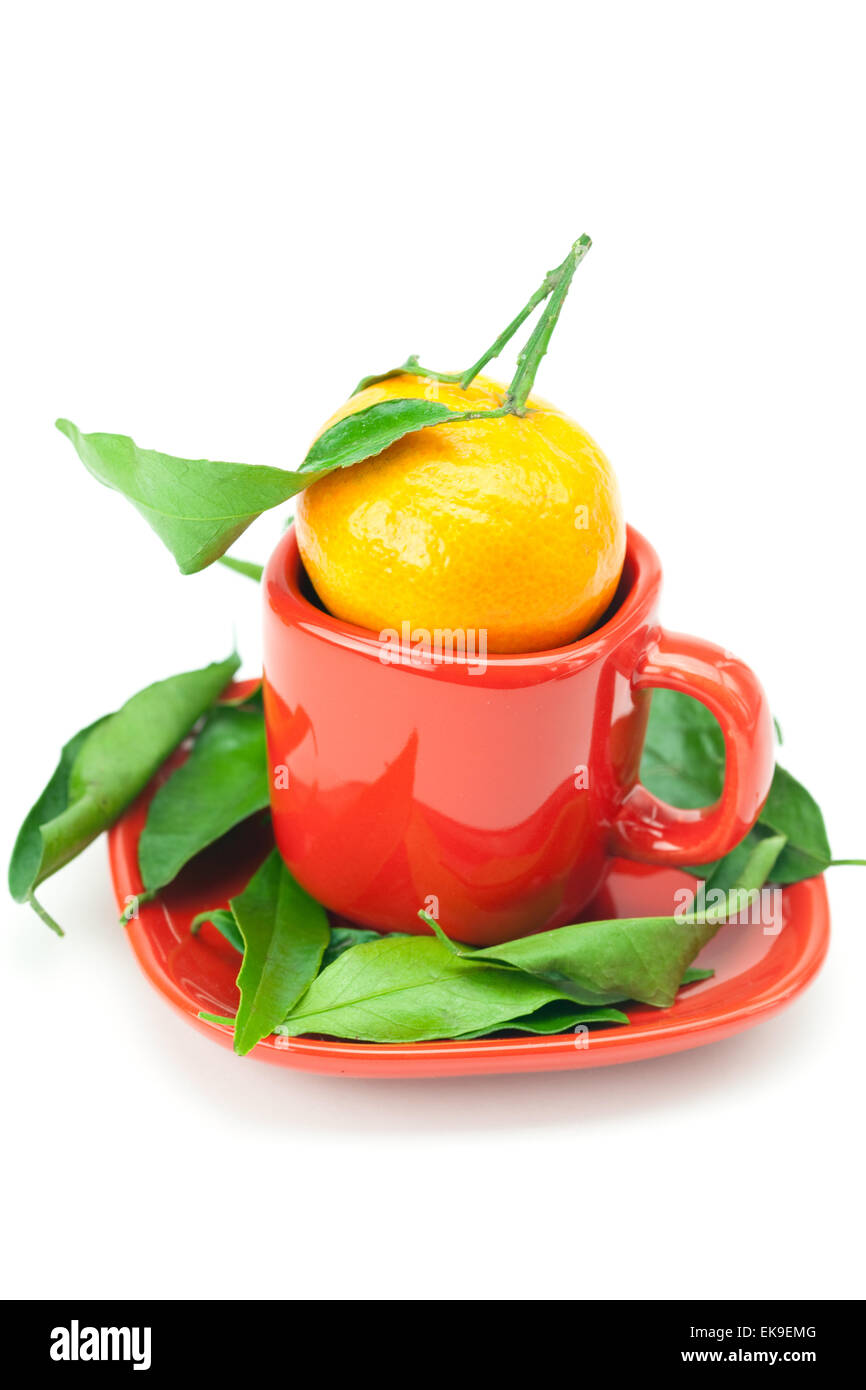 Il mandarino con il verde delle foglie in una tazza isolata su bianco Foto Stock