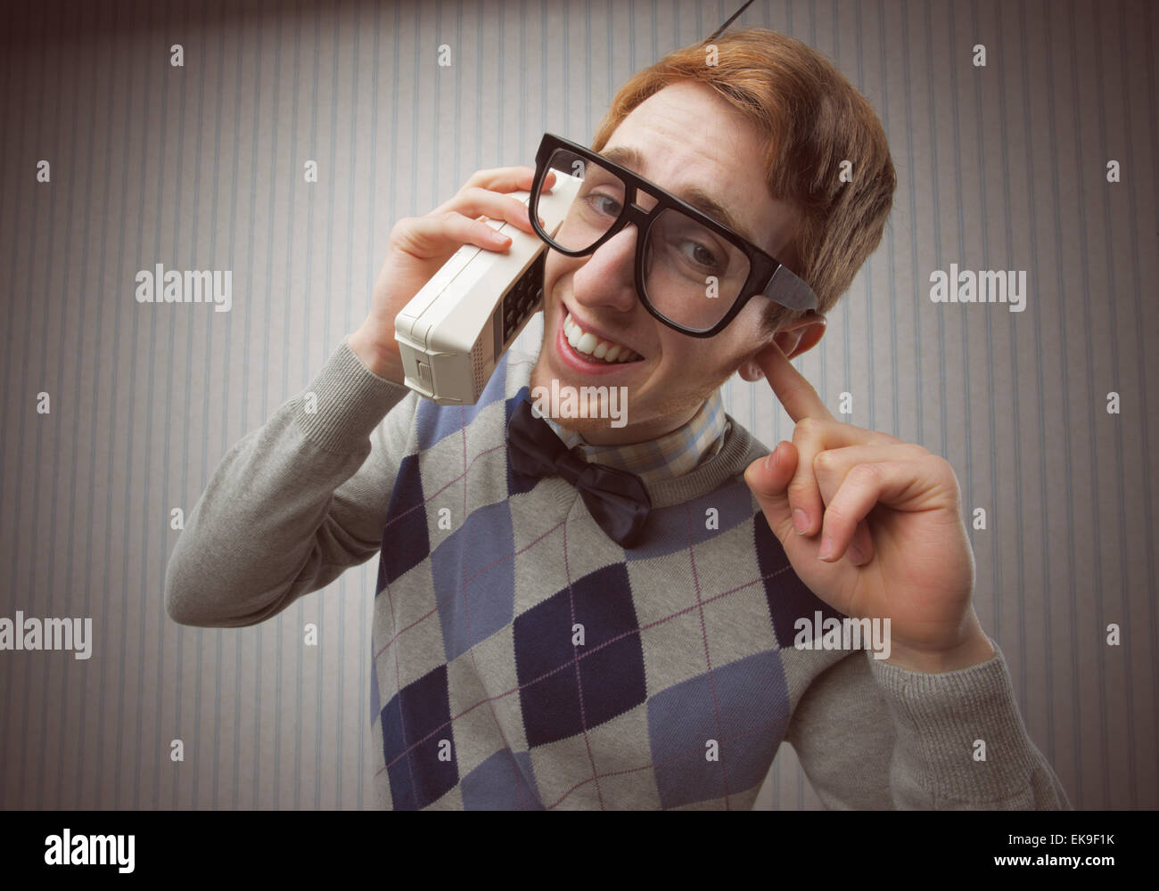 Nerd studente con un vecchio telefono cellulare Foto Stock