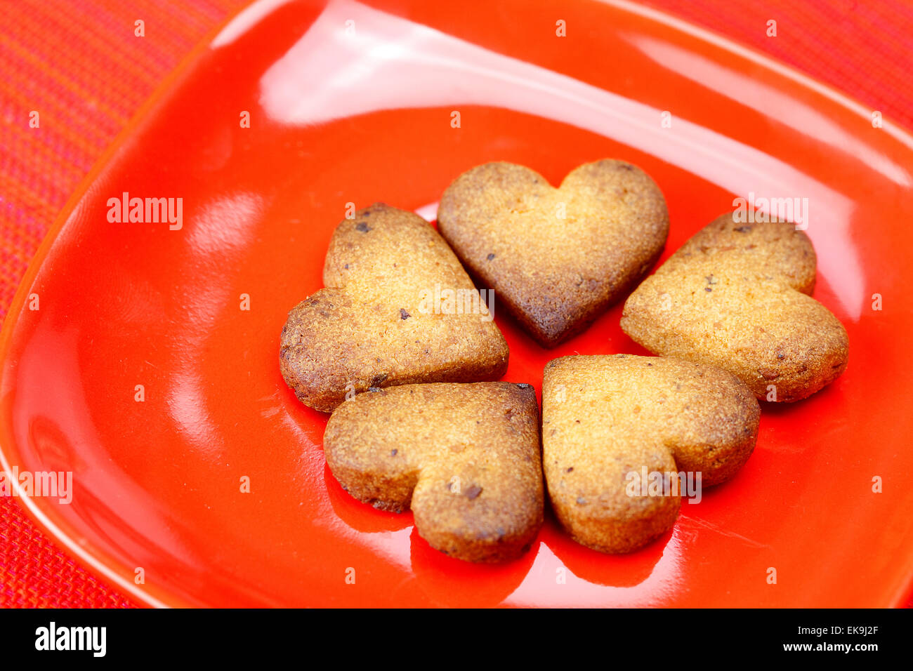 Biscotto a forma di cuore in una piastra su uno sfondo rosso Foto Stock