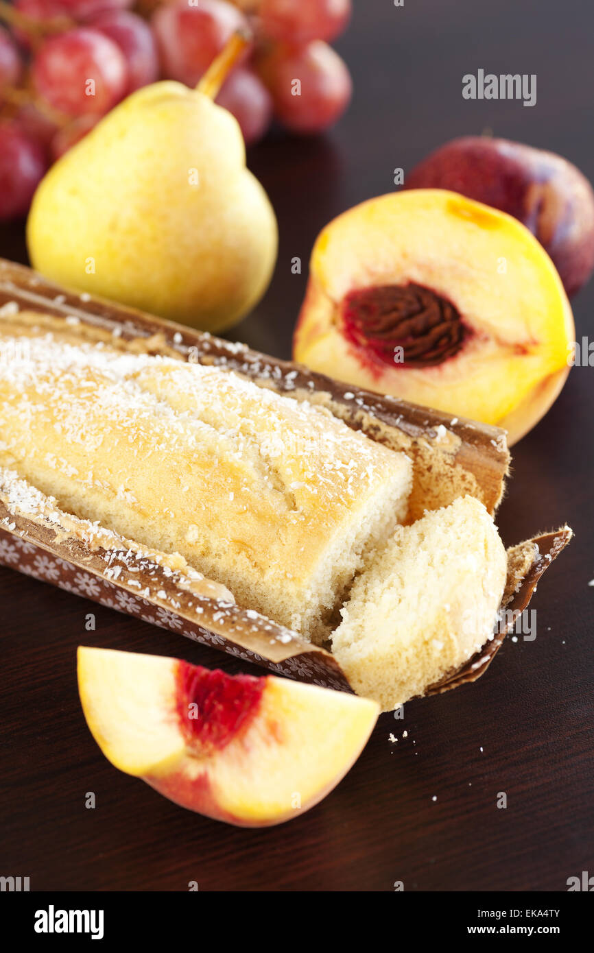 Pesca, pera, susina, torta di noci di cocco e uva su una tavola di legno Foto Stock