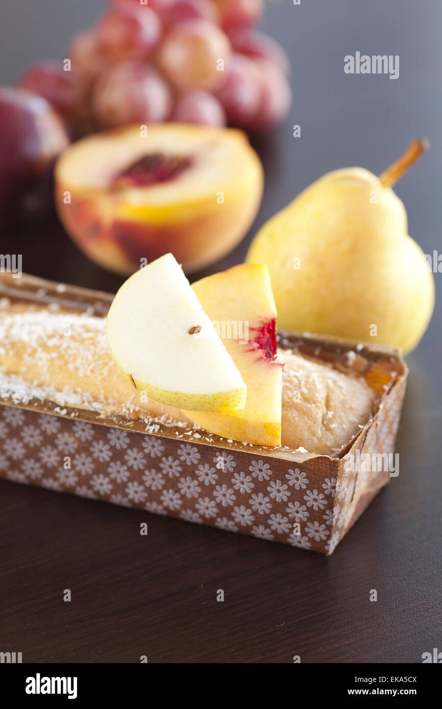 Pesca, pera, susina, torta di noci di cocco e uva su una tavola di legno Foto Stock