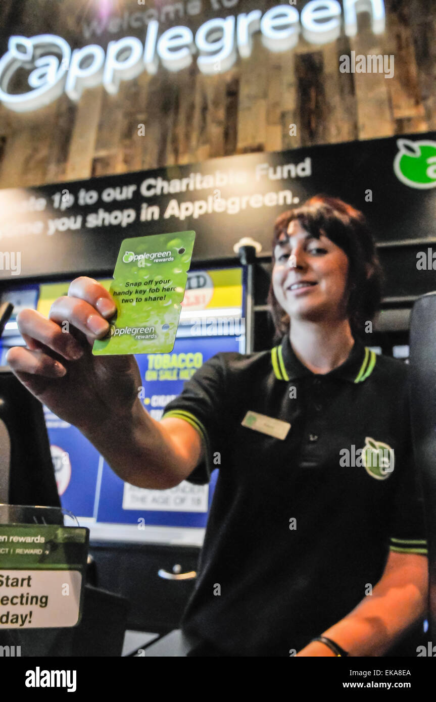Una donna offre a un cliente un Applegreen carta fedeltà Foto Stock