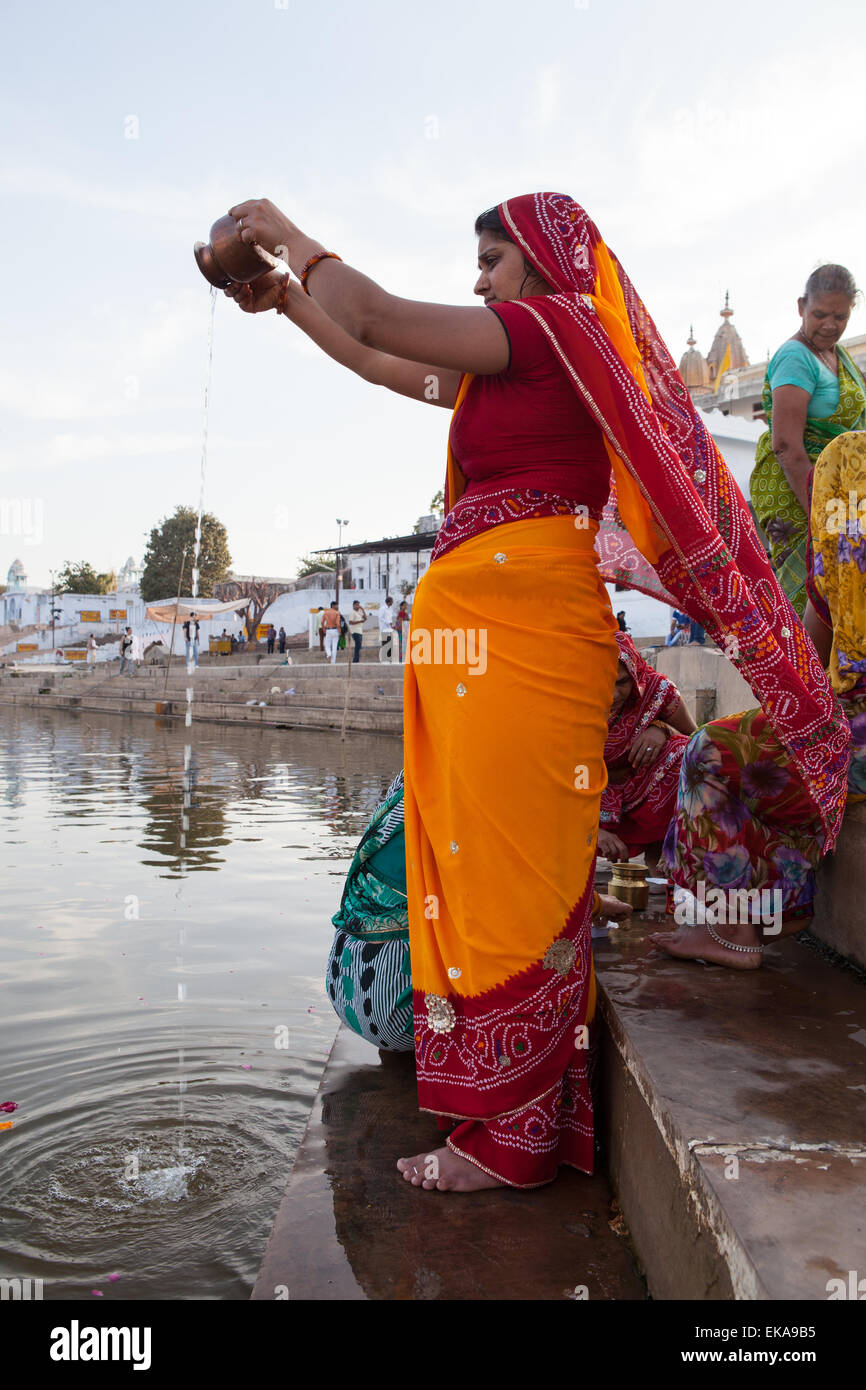 Un pellegrino si versa acqua nel Lago di Pushkar come parte del rituale puja Foto Stock