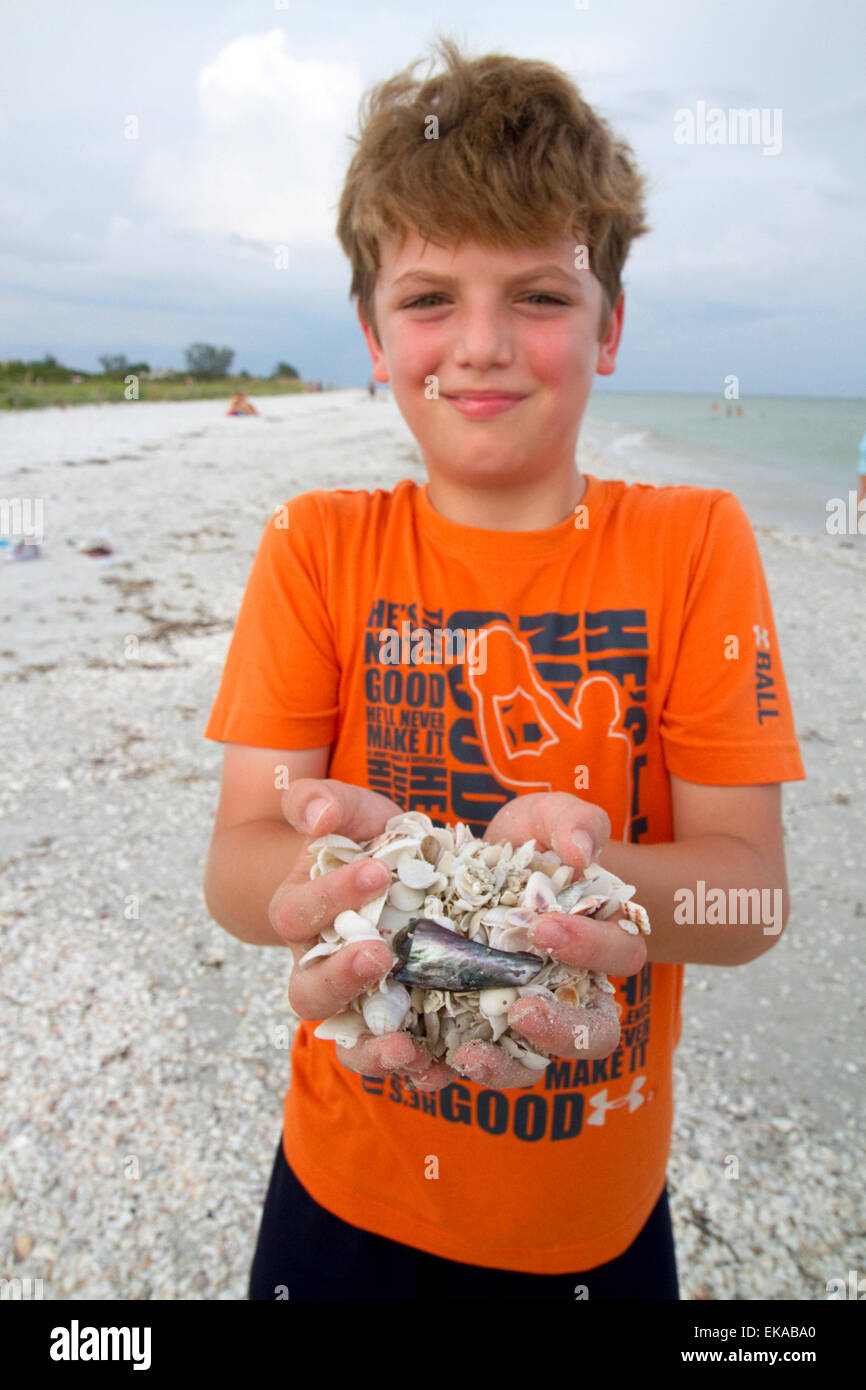 Dieci anni di vecchio ragazzo raccogliendo conchiglie sulla Gulf Coast Beach in Florida, Stati Uniti d'America. Foto Stock