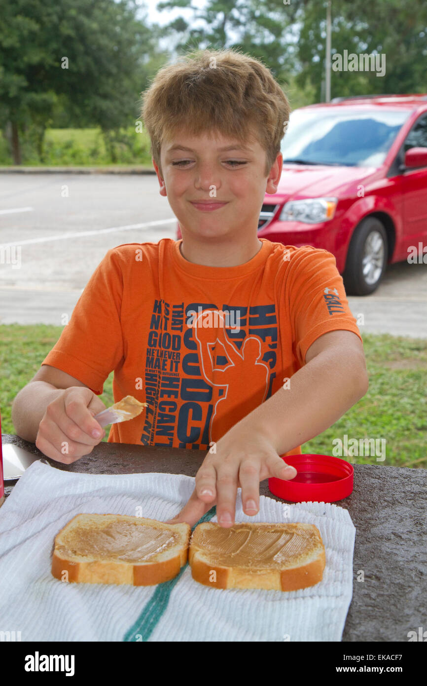 Dieci anni di vecchio ragazzo facendo un sandwich al burro di arachidi. Foto Stock