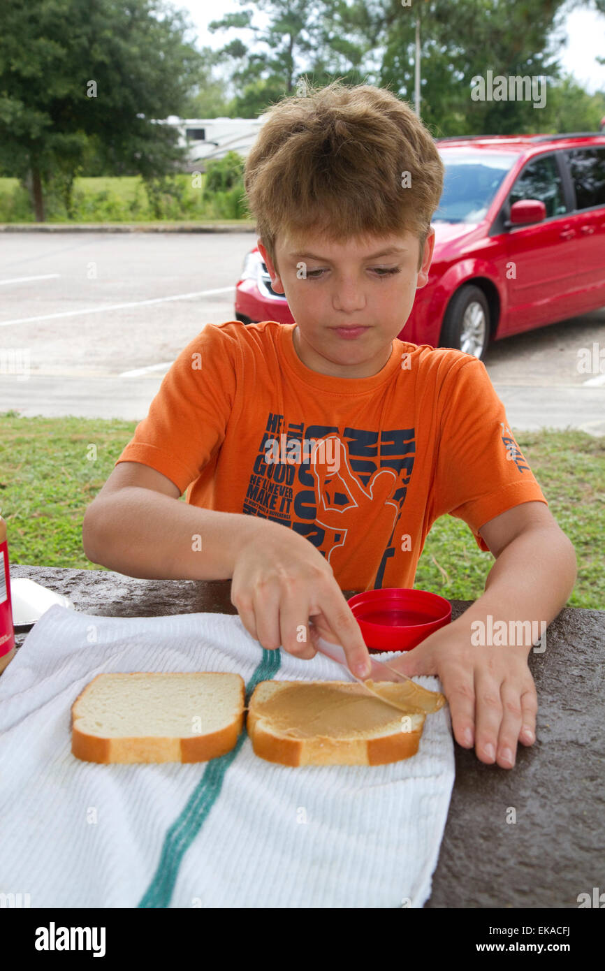 Dieci anni di vecchio ragazzo facendo un sandwich al burro di arachidi. Foto Stock
