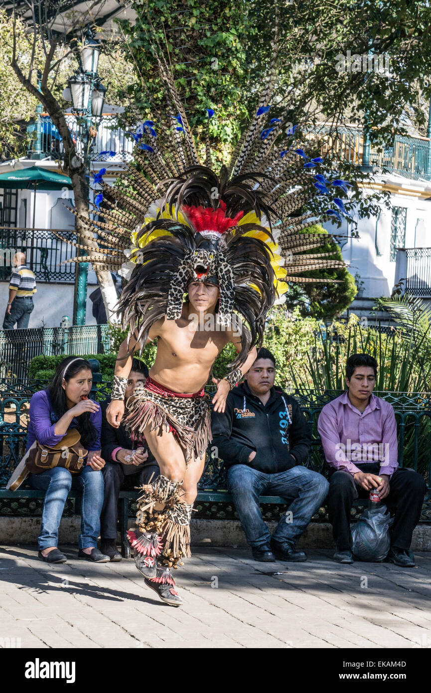 Muscolare di giovani indigeni uomo in perizoma & elaborata jaguar piumati copricapo danze nel Zocalo di San Cristobal de las Casas Foto Stock