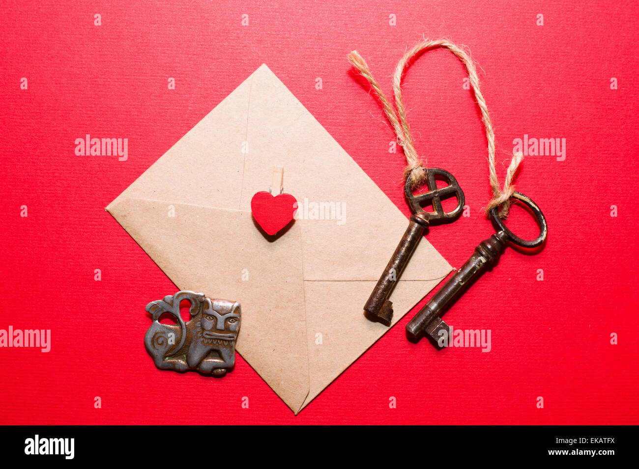 Busta con cuore, due chiavi vecchie e poco monster su uno sfondo di colore rosso. Foto Stock