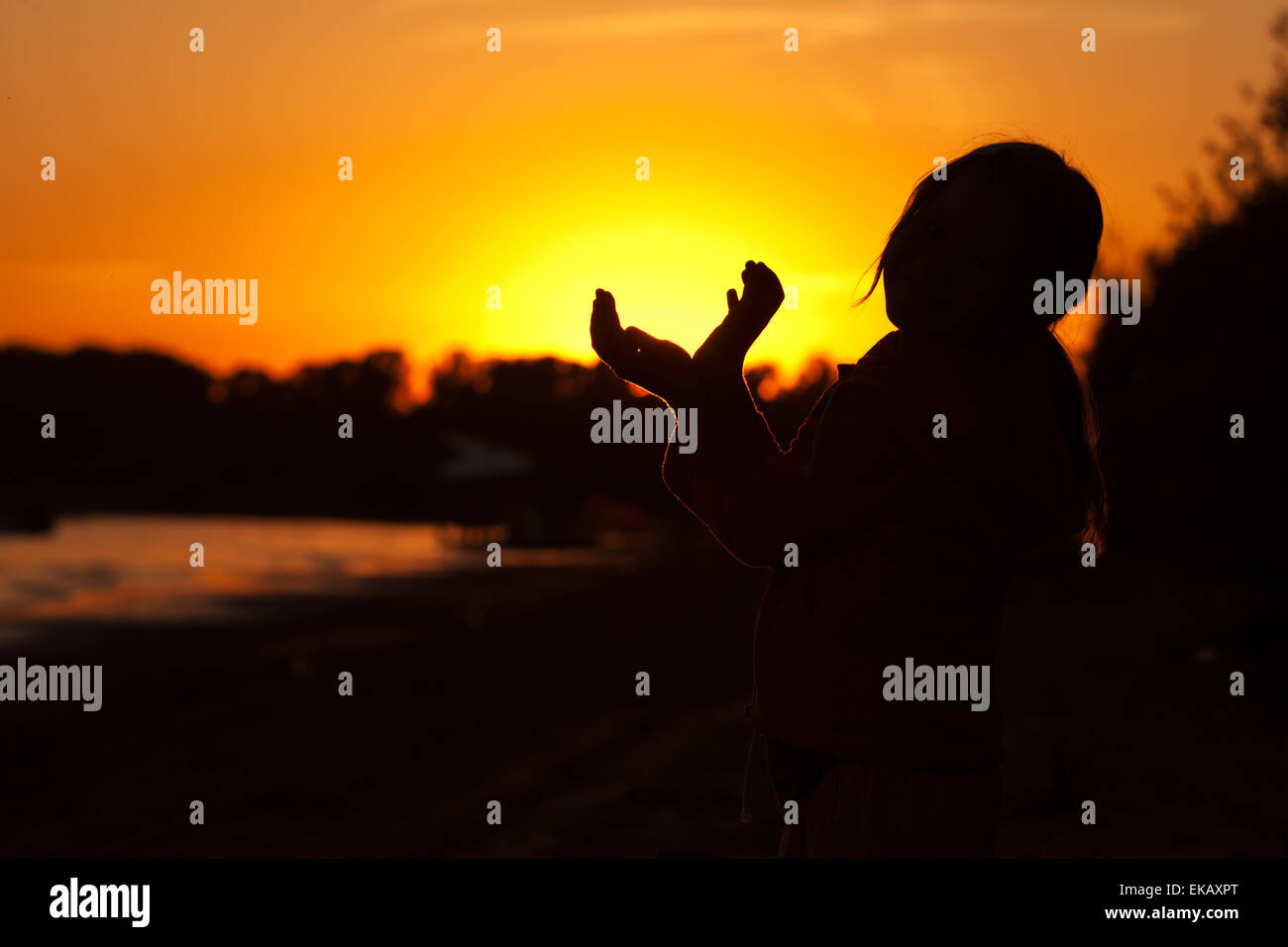 Bambina tenendo in mano il sole di setting Foto Stock