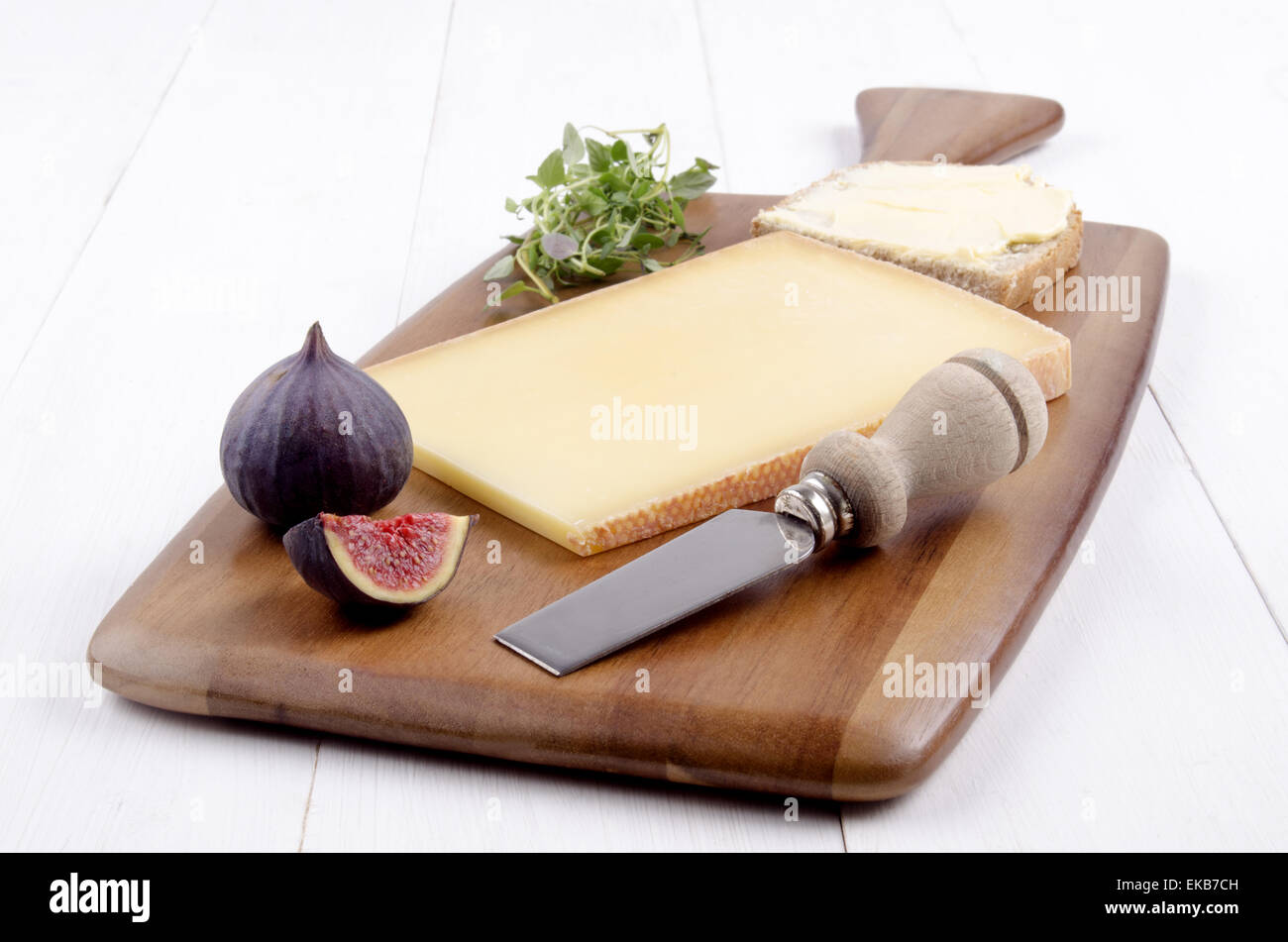 Svizzero di formaggio a pasta dura, di timo fresco, fig, Coltello per formaggio e pane con burro su un marrone di legno Foto Stock