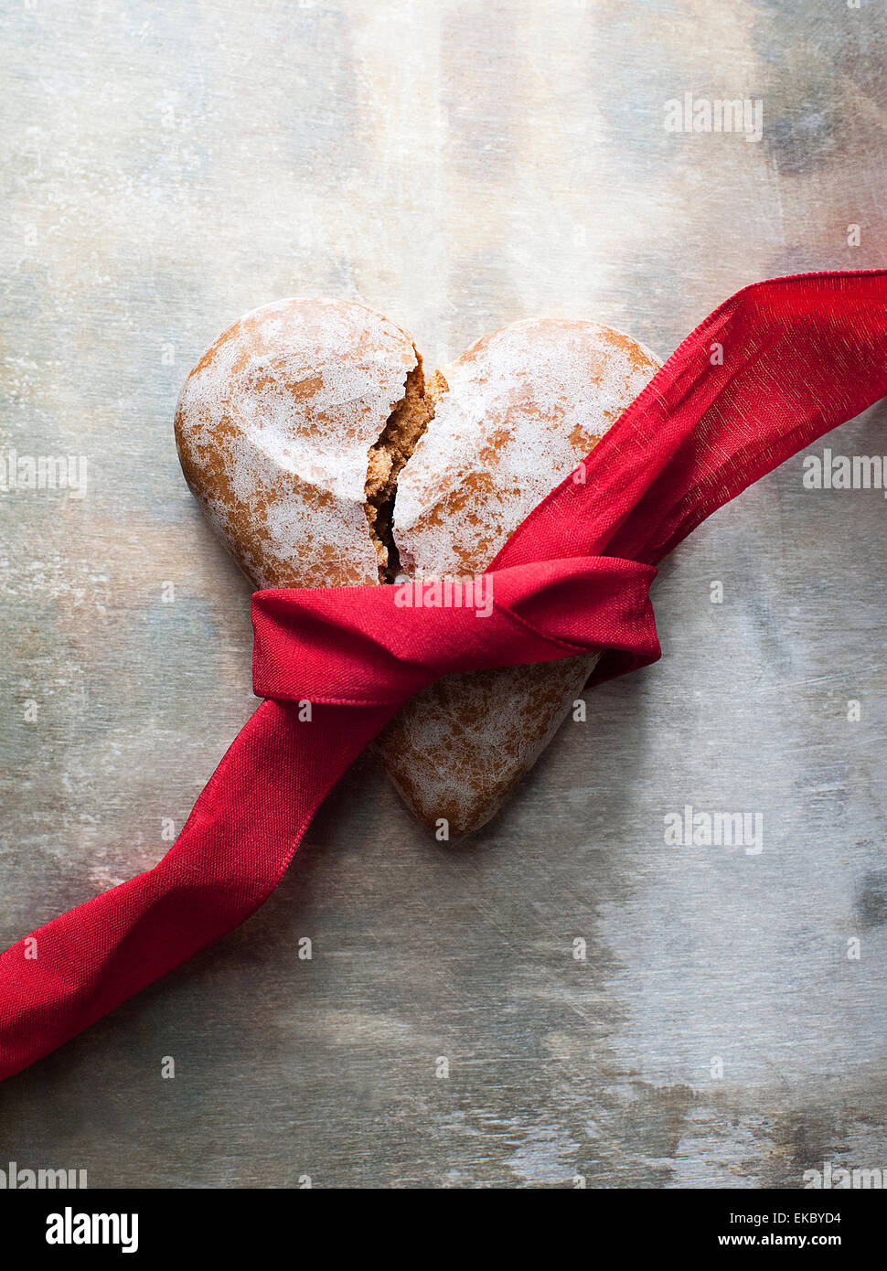 Broken heart-shaped gingerbread cookie con nastro rosso Foto Stock