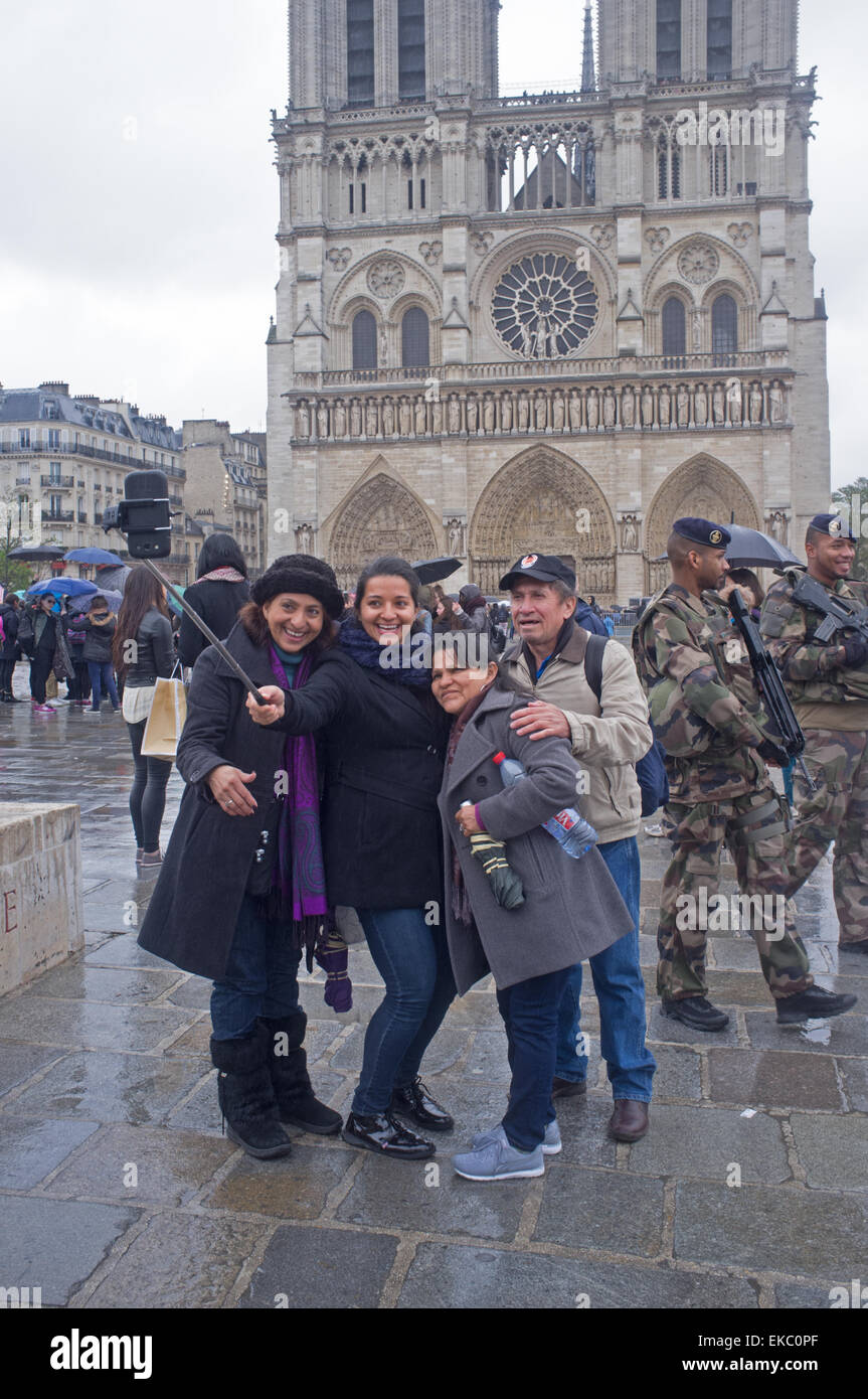 I turisti prendendo un selfie al di fuori di Notre Dame con l esercito francese soldati passante Foto Stock