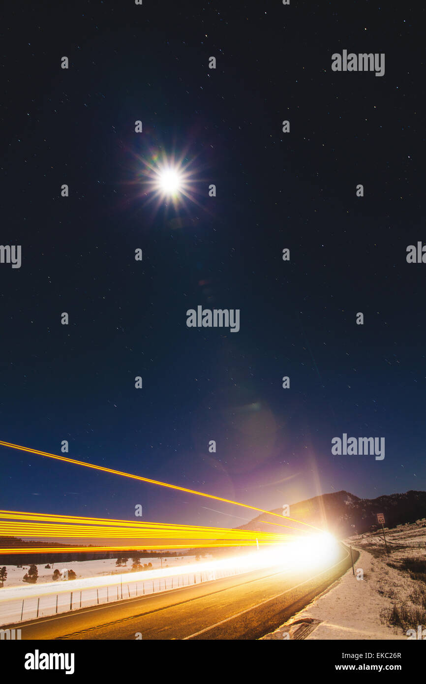 Autostrada sentieri di luce e la luna piena di notte, Pagosa Springs, Colorado, STATI UNITI D'AMERICA Foto Stock