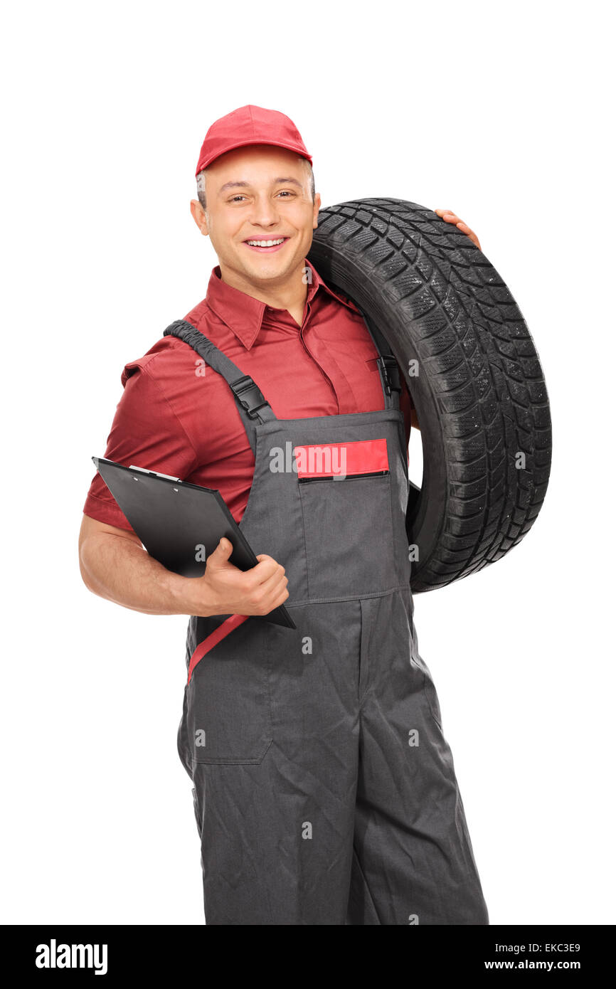Colpo verticale di un maschio di lavoratore manuale in grigio di una tuta tenendo un blocco appunti e un pneumatico isolato su sfondo bianco Foto Stock