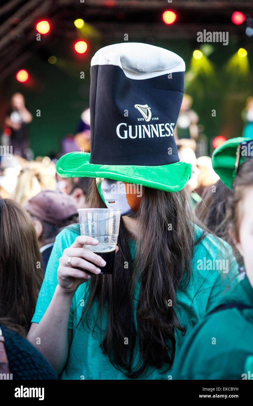Festa di San Patrizio. Guinness bere giovane femmina partying in una folla. Guinness hat, maschera di Guinness, pinta di Guinness. Turismo Irlandese. Irlandese. Foto Stock