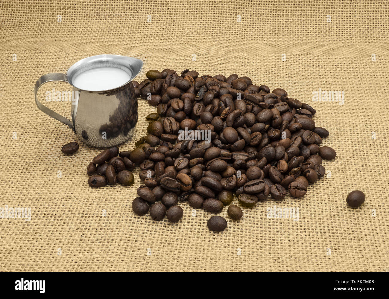 I chicchi di caffè e latte caraffa sulla tela dello sfondo. Foto Stock