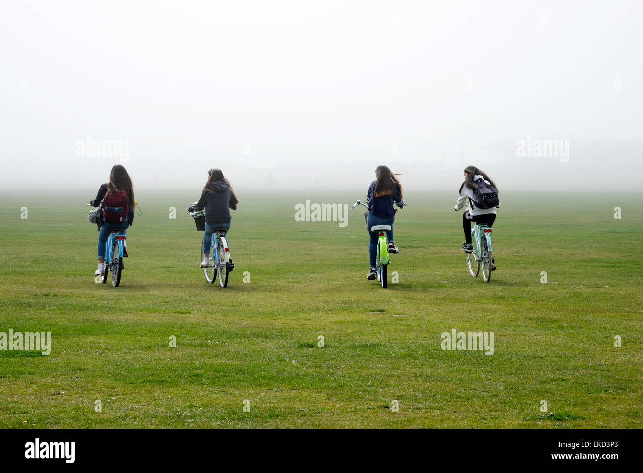 Quattro giovani femmine godetevi un giro in bicicletta sul comune come una pesante foschia marina derive dal mare southsea England Regno Unito Foto Stock