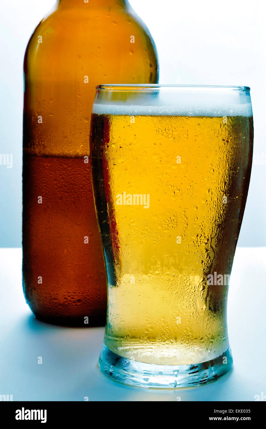 Una bottiglia e con un bicchiere di birra rinfrescante Foto Stock