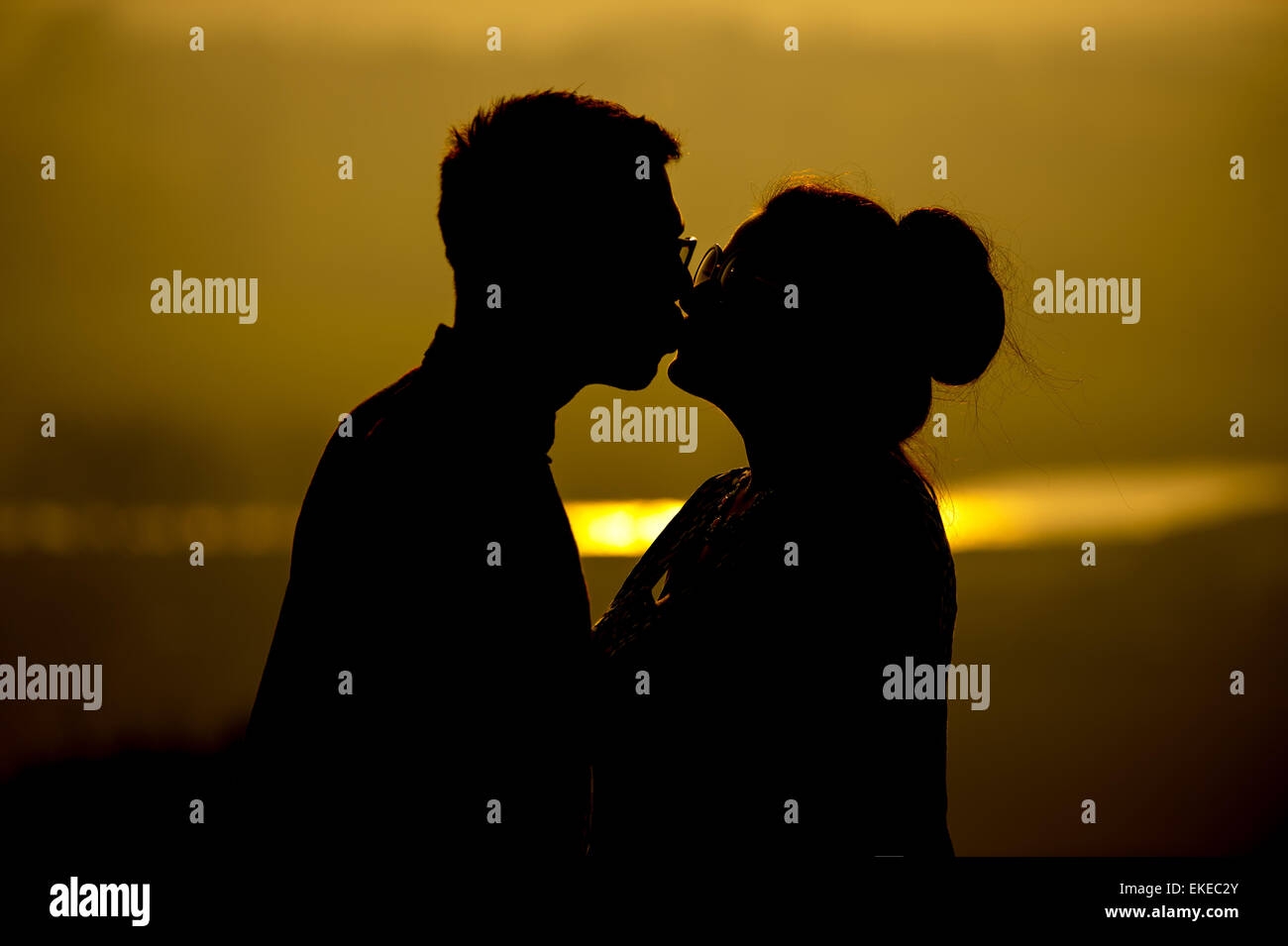 Un paio di abbracciare e condividere un bacio al tramonto su un vago estati giorno in Inghilterra, Regno Unito. Foto Stock