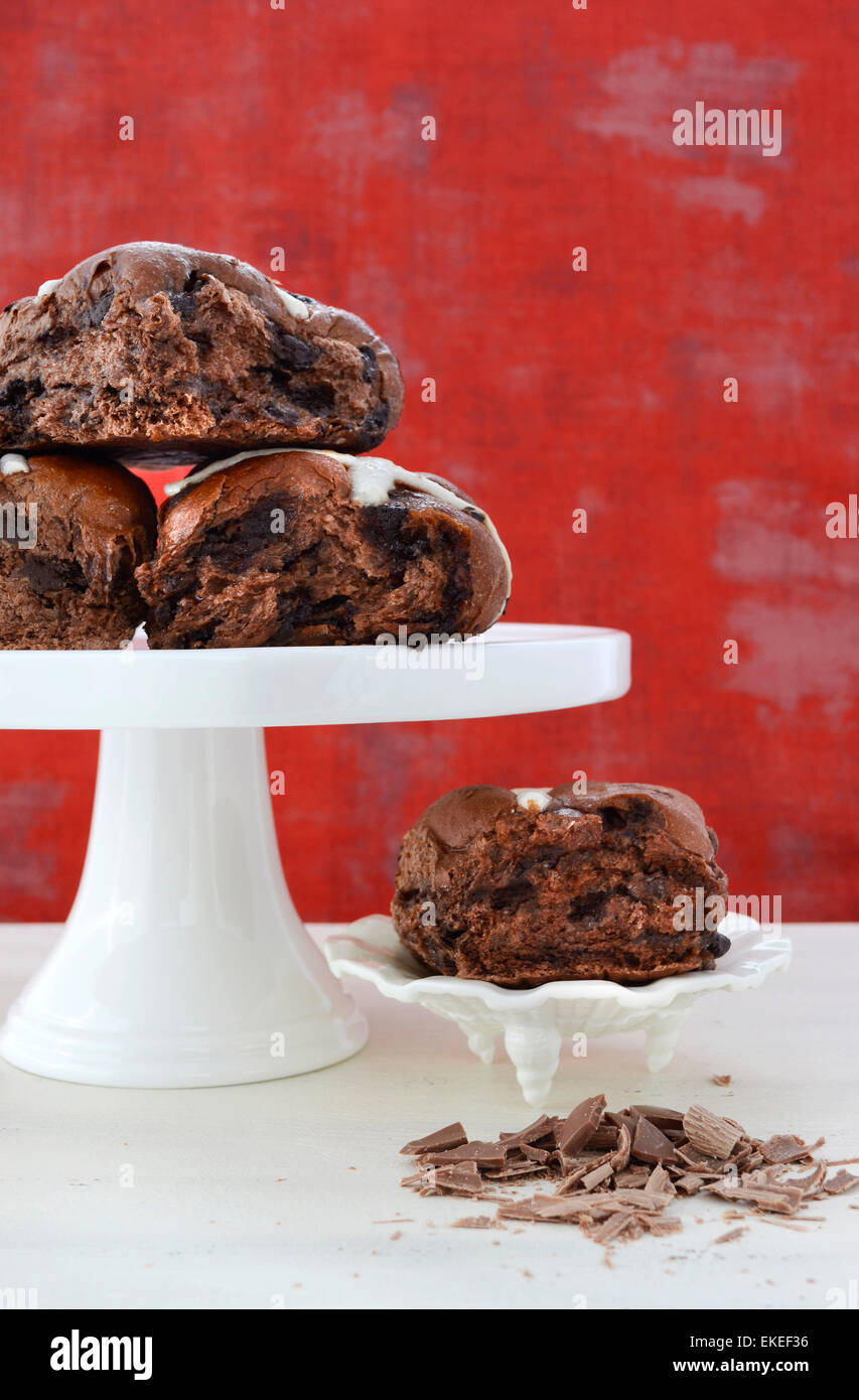 Cioccolato panini dolci di frutta sulla torta bianca Stand su bianco shabby chic tavolo in legno con sfondo rosso sfondo. Foto Stock