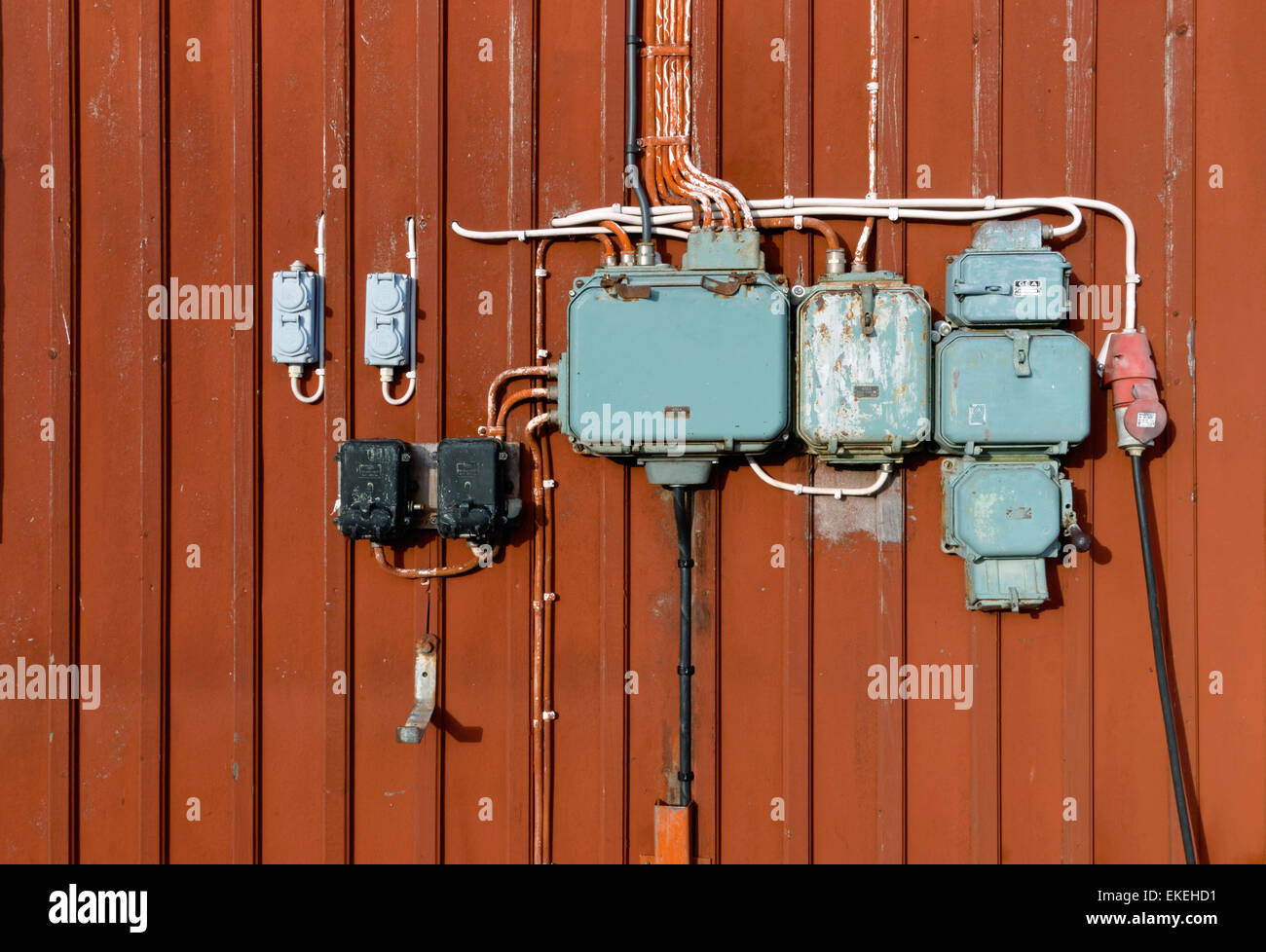 In stile retrò di circuiti elettrici, connettori femmina e le scatole di giunzione montato su un rosso parete in legno Foto Stock