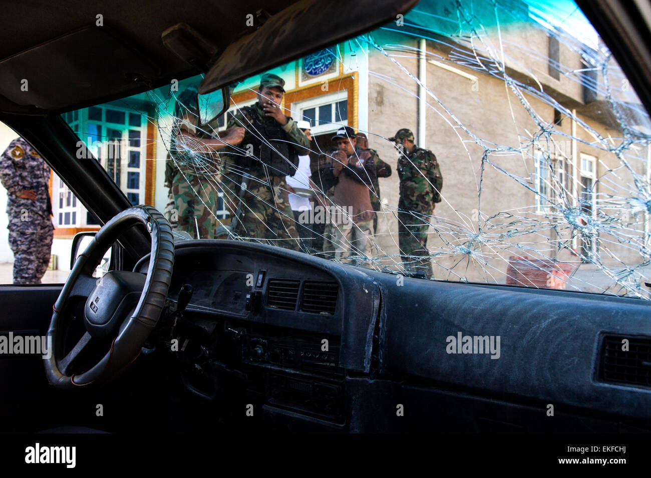 Di Tikrit, Iraq. 07 apr, 2015. I combattenti con lo sciita forze di mobilitazione Al-Hashd al-Shaabi prendere una pausa sigaretta davanti ad una vettura riddled con proiettili a Tikrit in Iraq, 07 aprile 2015. Foto: SEBASTIAN BACKHAUS/dpa/Alamy Live News Foto Stock