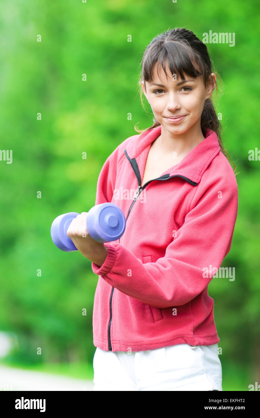 Ragazza facendo esercizio dumbbell outdoor Foto Stock