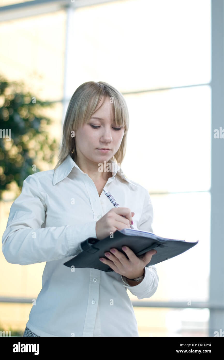 Giovane imprenditrice con il pianificatore di giorno nella lobby Foto Stock