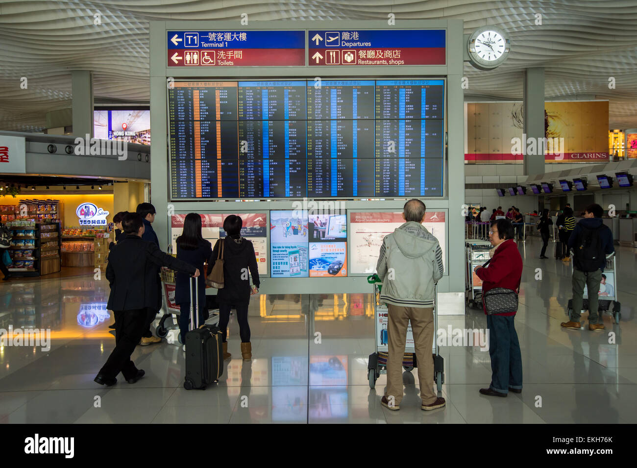 Passeggeri guardando il display di partenza a Hong Kong Airport Foto Stock