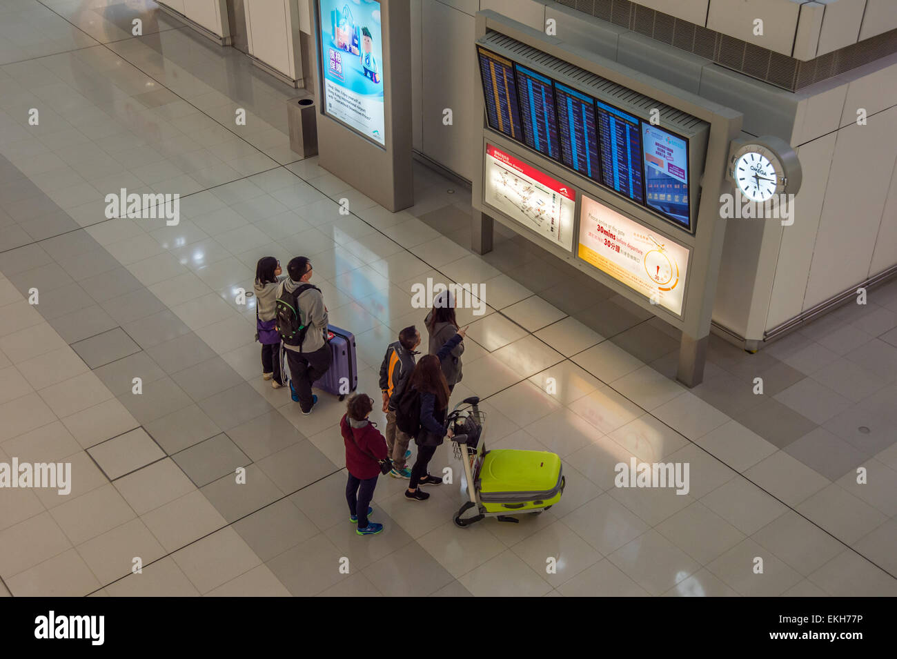 Passeggeri guardando il display di partenza a Hong Kong Airport Foto Stock