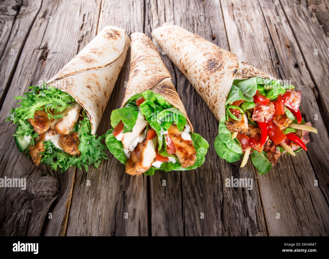 Fette di pollo in una Tortilla avvolgere con lattuga su legno. Foto Stock