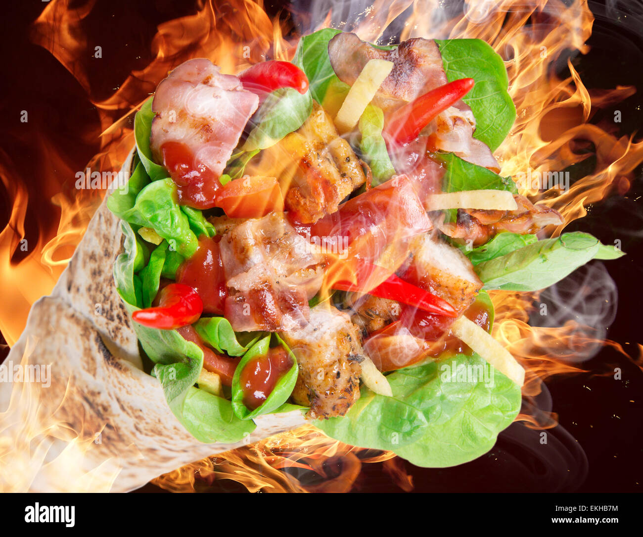 Fette di pollo in una Tortilla avvolgere con fiamme di fuoco. Foto Stock