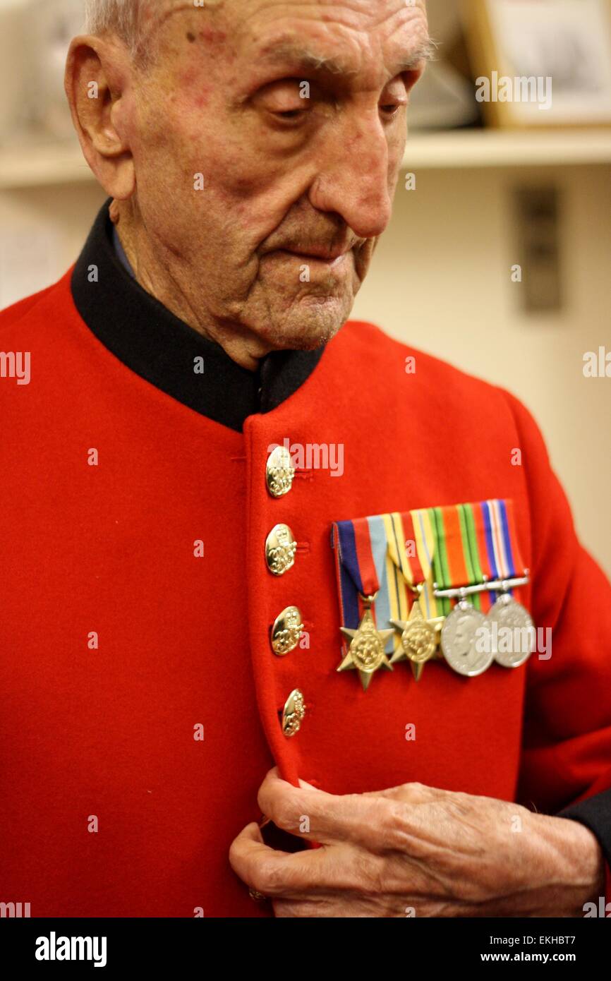 Il più anziano pensionato, Joe Britton, 104 anni, mettendo sul suo mantello scarlatto. Foto Stock