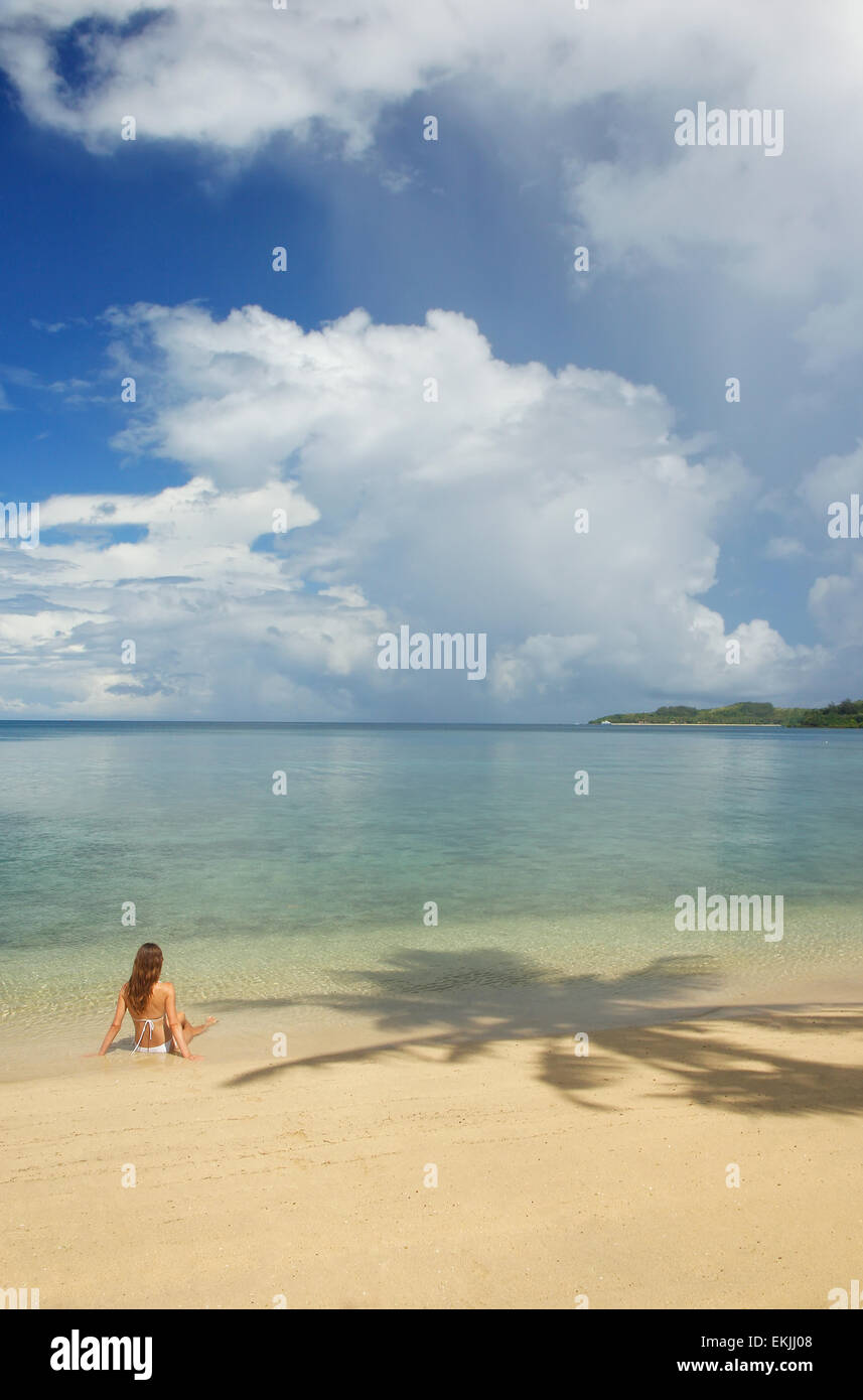Giovane donna in bikini seduto su una spiaggia tropicale, Nananu-i-Ra isola, Figi e Sud Pacifico Foto Stock